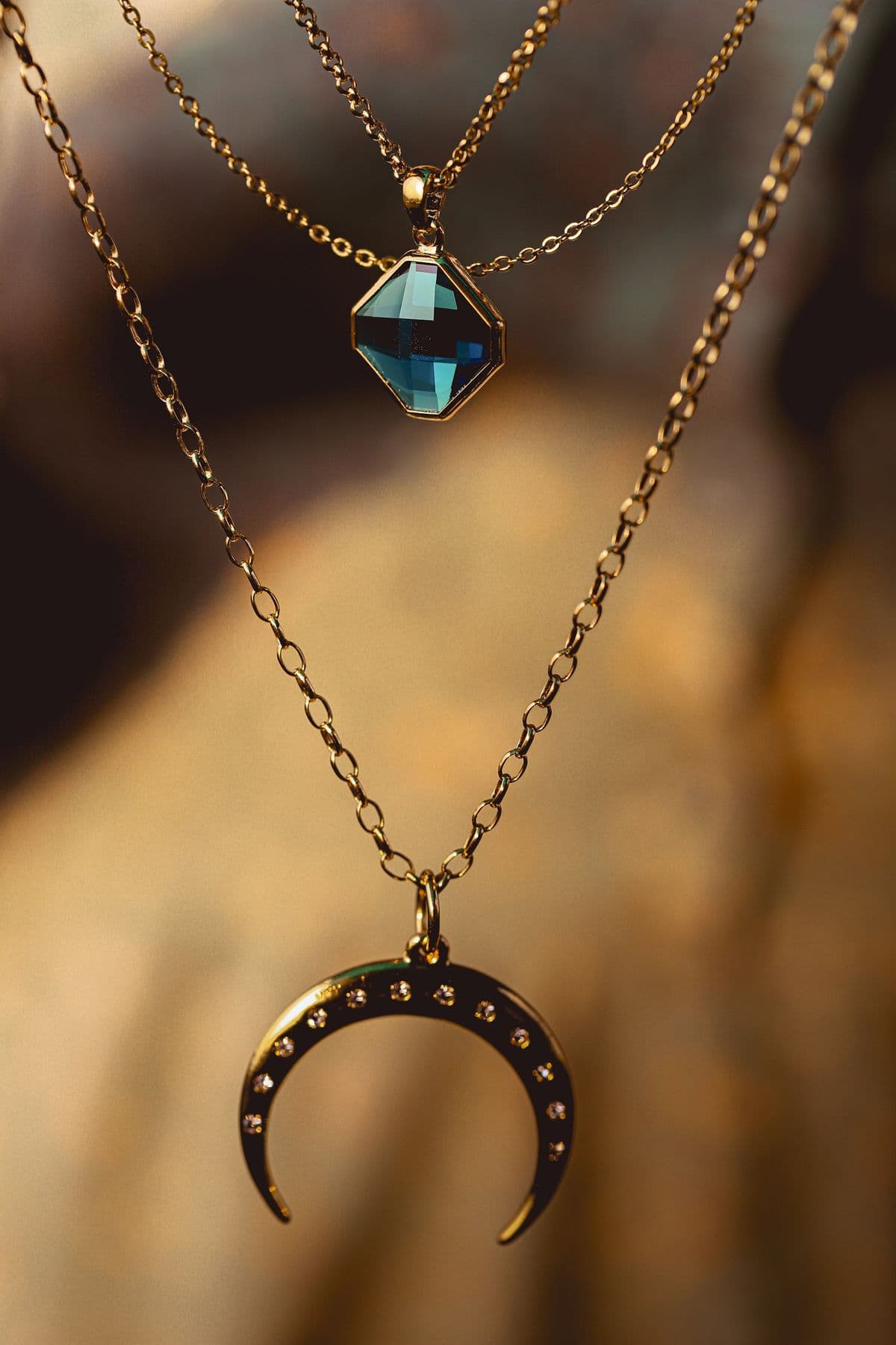 Layered gold necklaces with crescent and crystal pendants